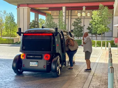 Older couple boarding dark grey Amazon Zoox self-driving pod.