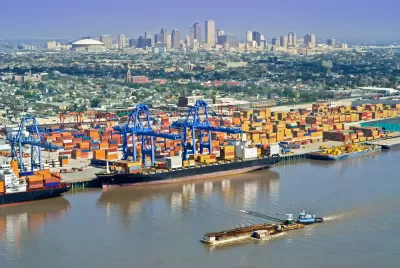 Aerial view of New Orleans port with cranes and barges and skyline in background