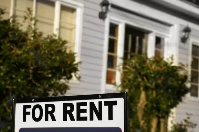 For rent sign with blurry house in background