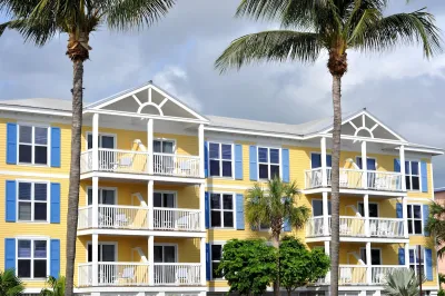 Colorfull light yellow and blue apartment building with tall palm trees in front in Florida.