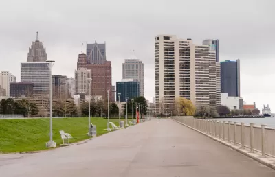 Waterfront walkway with benches and Detroit skyline in the background