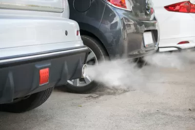 Close-up of back of three cars in a line with smoke coming from tailpipes