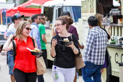 Food truck customers holding food with food trucks in background