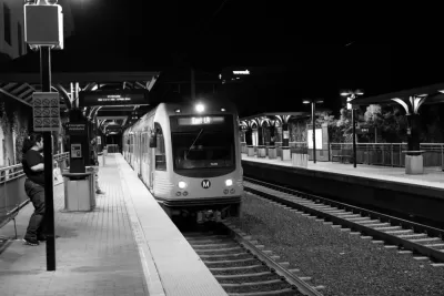 Black and white photo of Los Angeles Metro Gold Line train pulling into above-ground station at night, with one woman passenger waiting on platform.