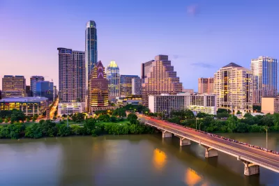 View of Austin, Texas skyline at dusk with Colorado River and bridge in foreground