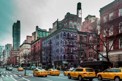View of New York City street with yellow cabs and purple and red brick apartment buildings in background
