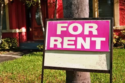 "For Rent" sign in yard of red building