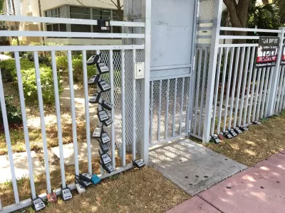 Gate in front of Miami Beach apartment building with many lock boxes for short-term renter access