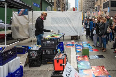 Artist painting live as people watch on New York City sidewalk.