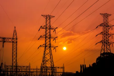Power lines and towers at a substation against a red sunset backdrop
