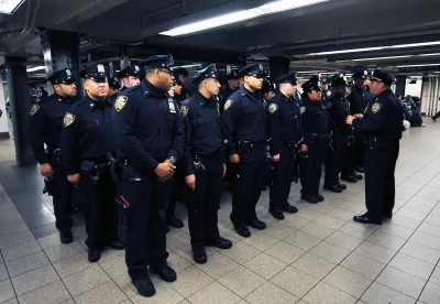 Rows of uniformed NYPD transit officers stand at attention in NYC subway station.