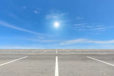 Vast, empty parking lot with blue sky and bright sun in background