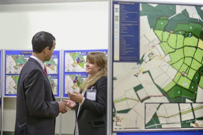 Man and woman talking in front of project presentation board at public meeting.