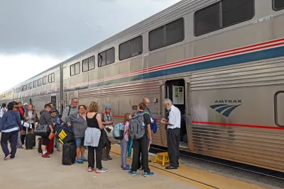 Passengers board an Amtrak train under a cloudy sky.