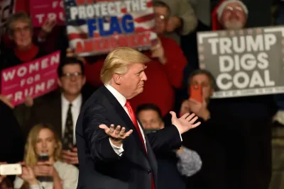 Trump at rally in Hershey, PA with person holding "Trump Digs Coal" sign visible in background.