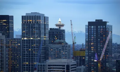 Seattle skyline at dusk with Space Needle and yellow construction cranes.