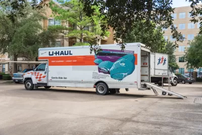 U-Haul moving truck with back door open and loading ramp down on residential street in Houston, Texas
