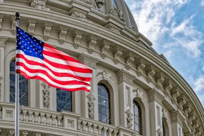 Close-up on Capitol Dome with American flag blowing in the wind in front of it.