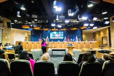 Person stands at podium to speak to city council or committee in government building in Austin, Texas.