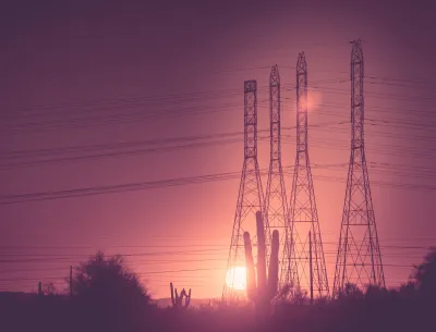Tall power line towers against sunset with saguaro cacti at bottom in Arizona.