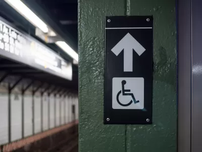 Accessible elevator sign with arrow on a New York City subway platform