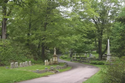 Gravestones along pathway in green Mount Auburn Cemetery