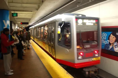 Blurred red Muni train passing by platform at underground station in San Francisco.