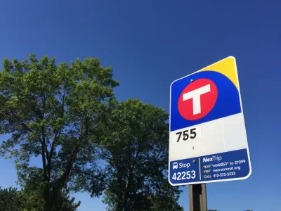 Close-up of red and blue MetroTransit bus stop sign against blue sky and green tree in New Hope, Minnesota