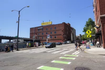 Pedestrians in zebra crosswalk with green bike lane in downtown Seattle, Washington with three-story brick building in background