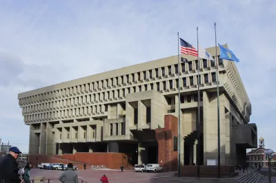 Brutalist Boston City Hall building with parking and people walking in front.