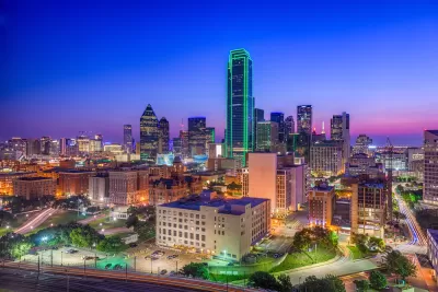 View of downtown Dallas skyline at night with tall tower lined with green lights