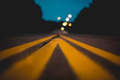 Blurred view from ground level of yellow center lines on asphalt street