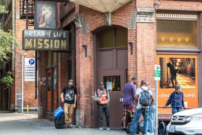 Several men stand waiting in front of Bread of Life Mission brick building in Seattle, Washington.