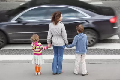 Mother and two young children waiting to cross street at busy crosswalk