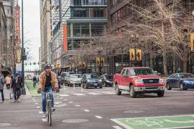 Chicago street with red truck and cyclist wearing helmet riding in green painted bike lane.