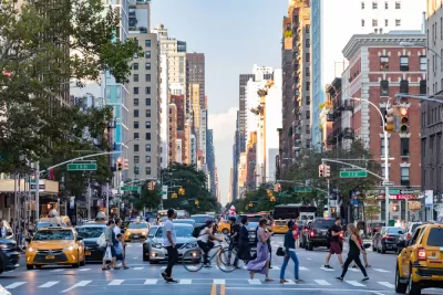 Pedestrians crossing a busy crosswalk on New York City street with tall buildings in background