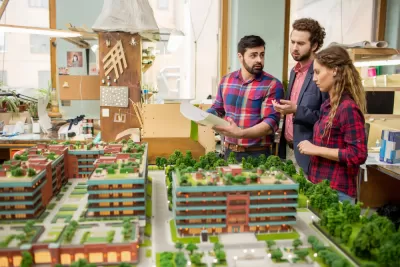 Three planners or architects standing over a model of buildings and greenery and discussing