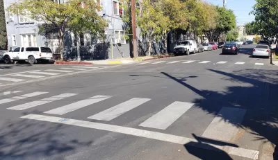 A white crosswalk painted by Crosswalk Collective LA in Los Angeles, California.
