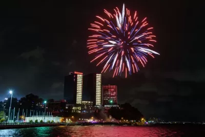 Nighttime view of tall buildings with red fireworks going off in a distance