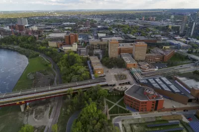 University of Minnesota Humpharey primary image of the city scape, a body of water on the left side, and a bridge running across the lower half of the image.