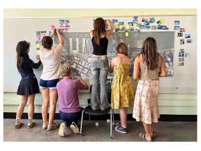 Group of students in a classroom posting colored postits up on the wall for a group excersize