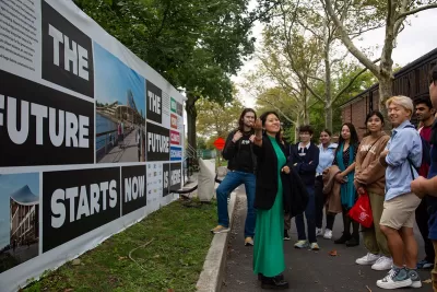 New York City group tour with students outside next to a wall that says "The future Starts Now" standing on grass