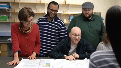 Image of people gathered around a table discussing something