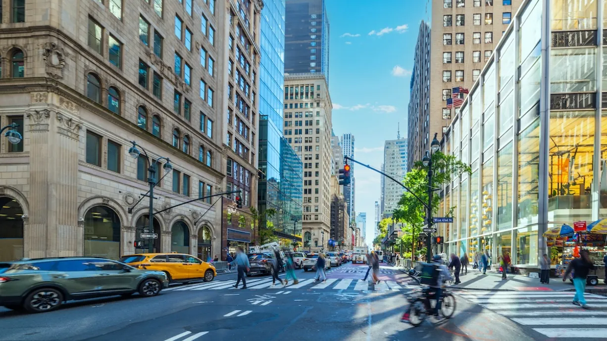 Crosswalk in New York City with cars, bikes, and pedestrians.