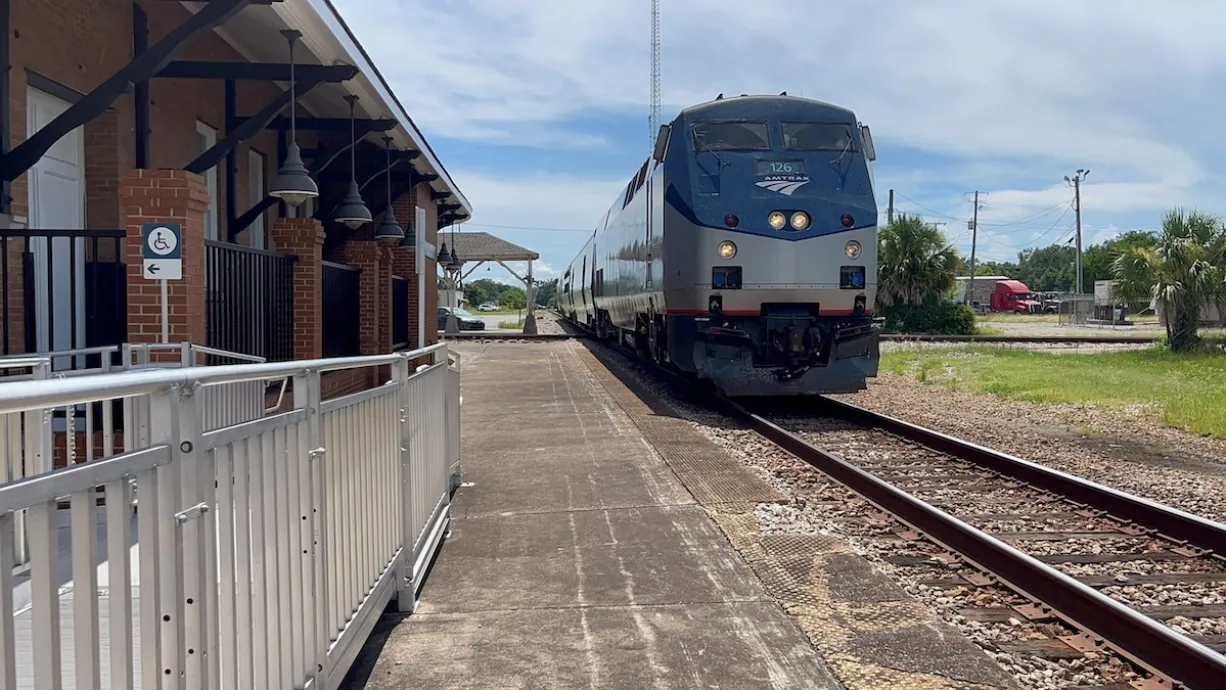 Blue and silver Amtrak train at small station.