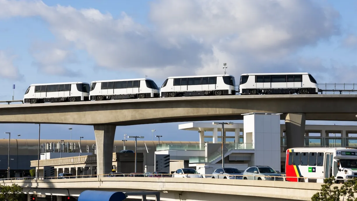 Four cars of the LAX SkyLink. They are white, and there is no clear front or back. They have black windows.