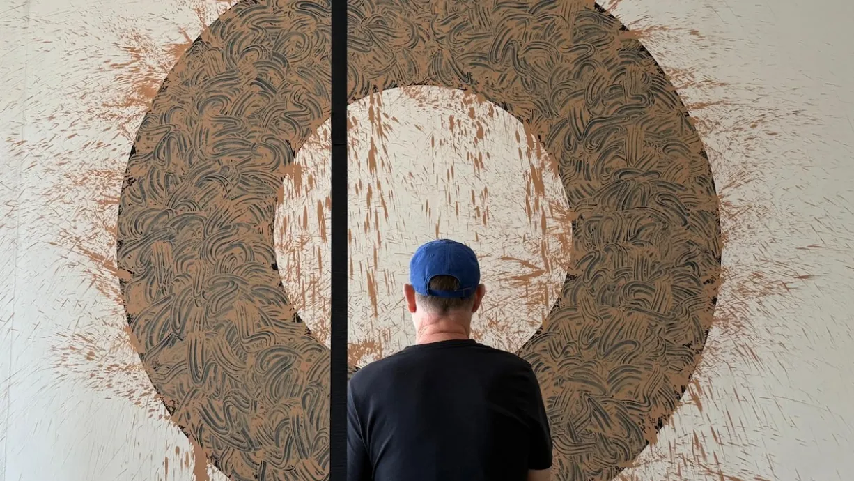 Photo of man looking at large painting.