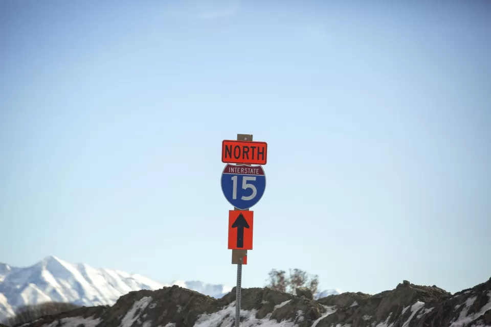 Blue and white Interstate 15 North sign against backdrop of blue sky and snow-capped mountains in Utah