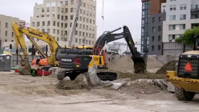 Yellow electric excavator digging at construction site in Los Angeles, California.