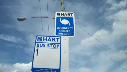 Close-up of HART bus stop sign for Route 1 and hurricane evacuation route sign on street pole in Tampa, Florida.